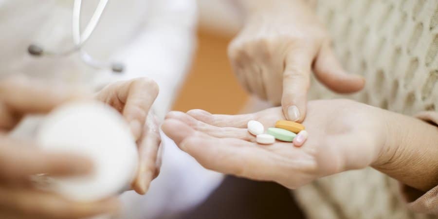 Patient pointing to medication in palm of their hand